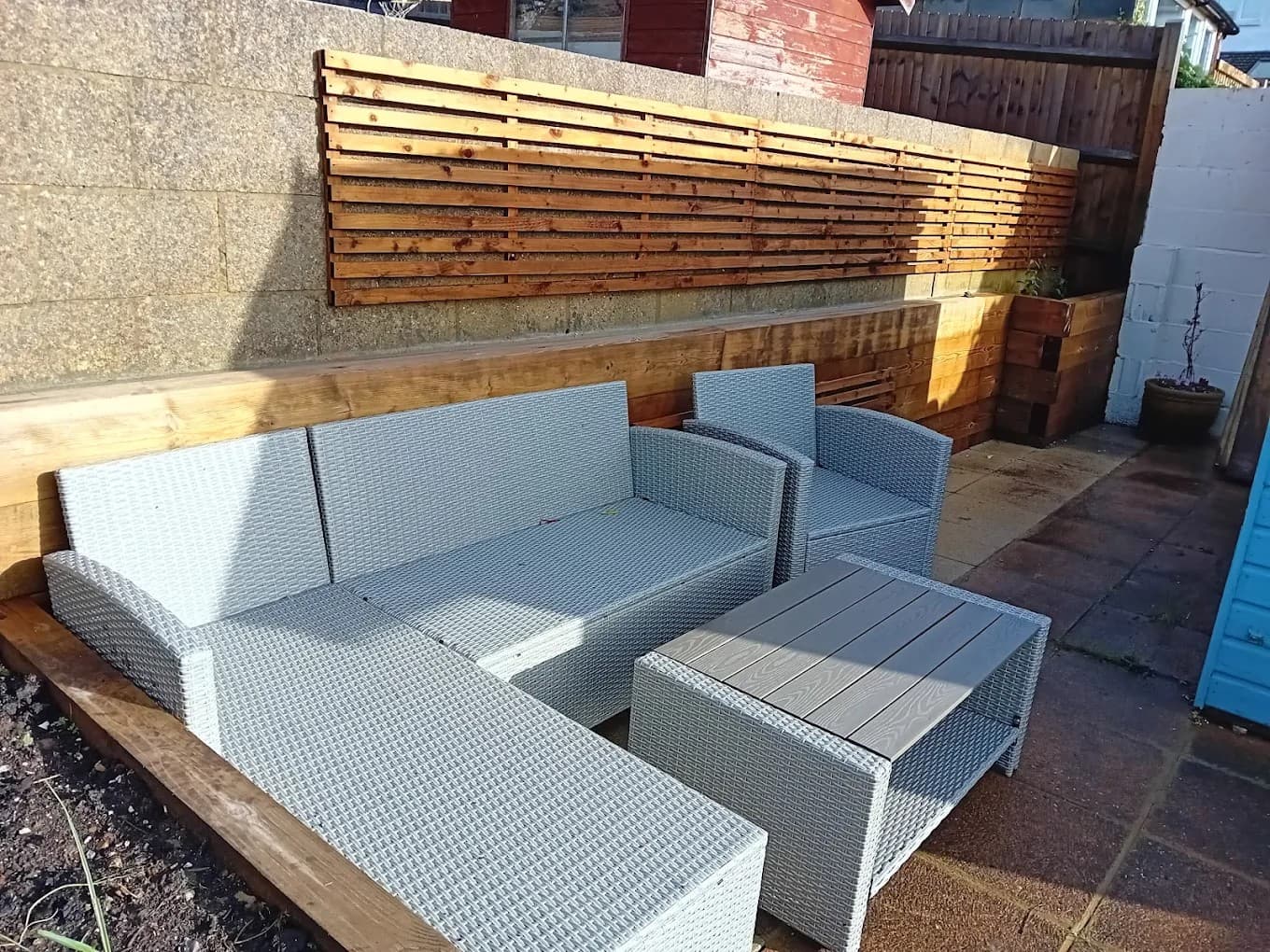 After – contemporary corner seating area with timber cladding and rattan furniture in a landscaped Brighton garden.