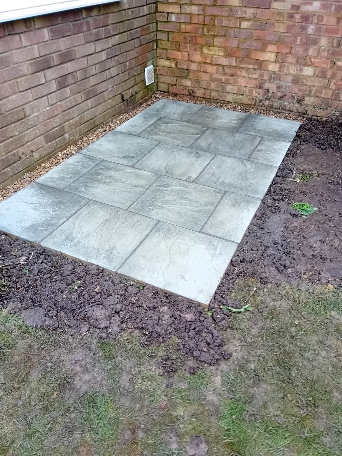 Newly installed compact grey slab patio with clean edges in Beeding, completed after full groundwork preparation.
